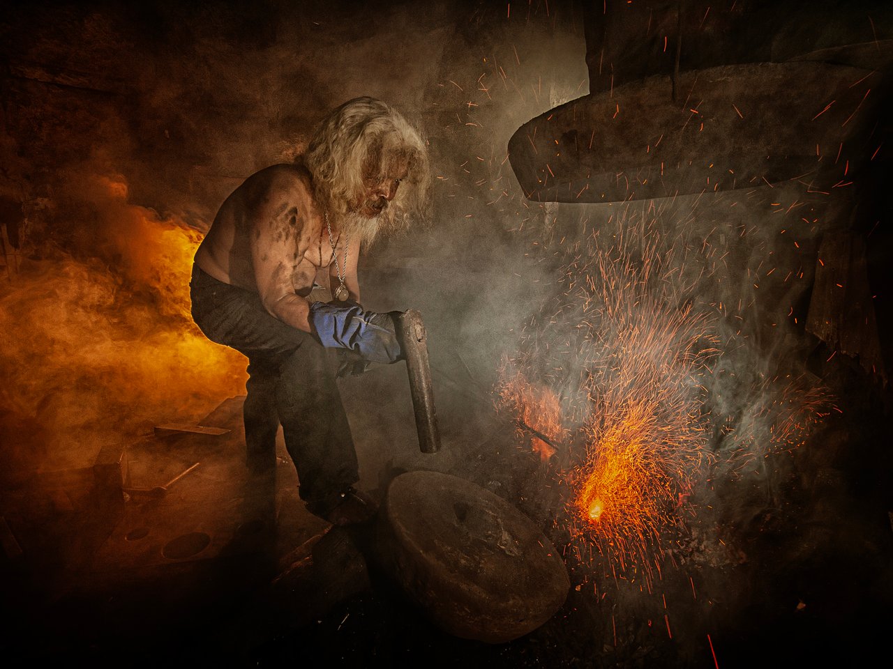A blacksmith in Cimahi, Indonesia, crafts metal amidst fiery sparks, showcasing traditional craftsmanship.